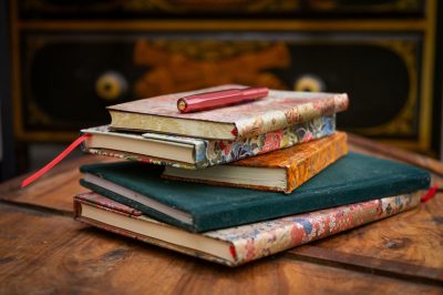 Stapel gekleurde schrijfboekjes op een houten tafeltje.
